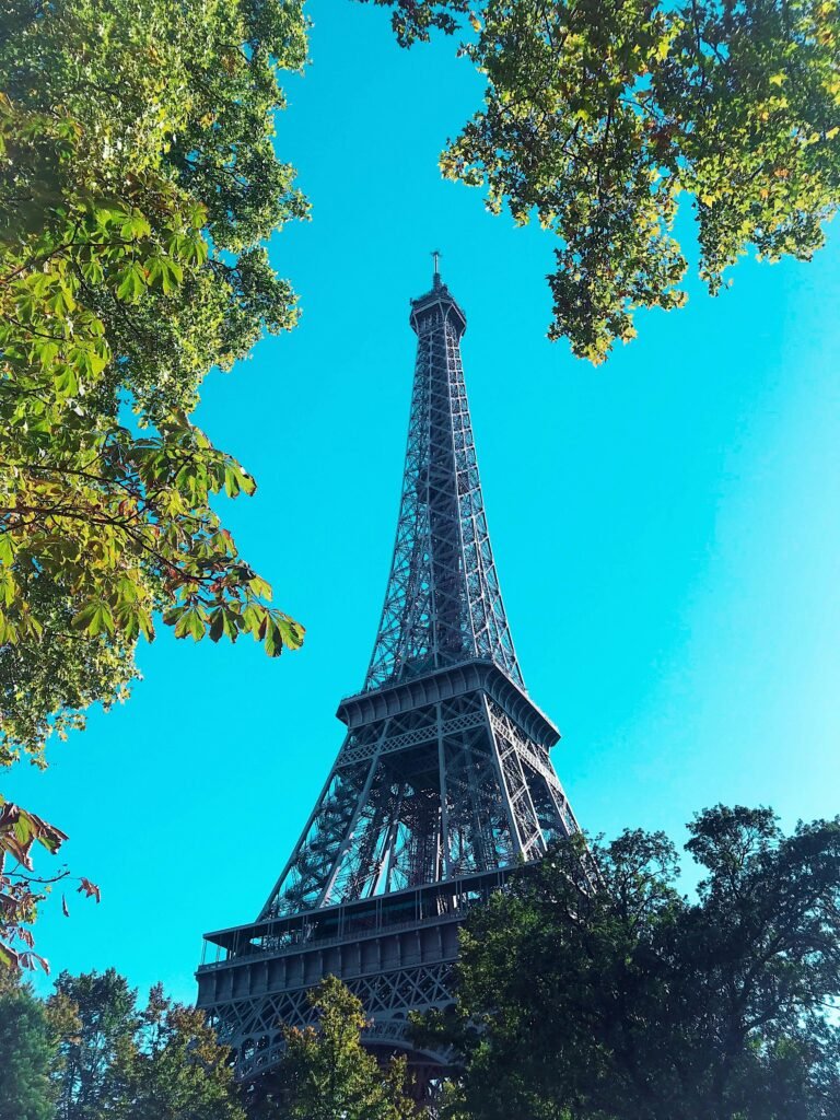 pexels-photo-1426719-1426719 A captivating view of the Eiffel Tower framed by lush trees on a sunny day in Paris.