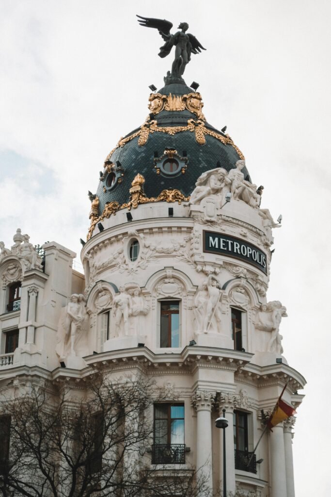 pexels-photo-3757136-3757136 Iconic Metropolis Building dome in Madrid captured in daylight, showcasing intricate architectural details and sculptures.